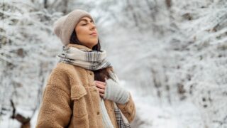 Beautiful woman breathing fresh air in a snowy forest. Winter time