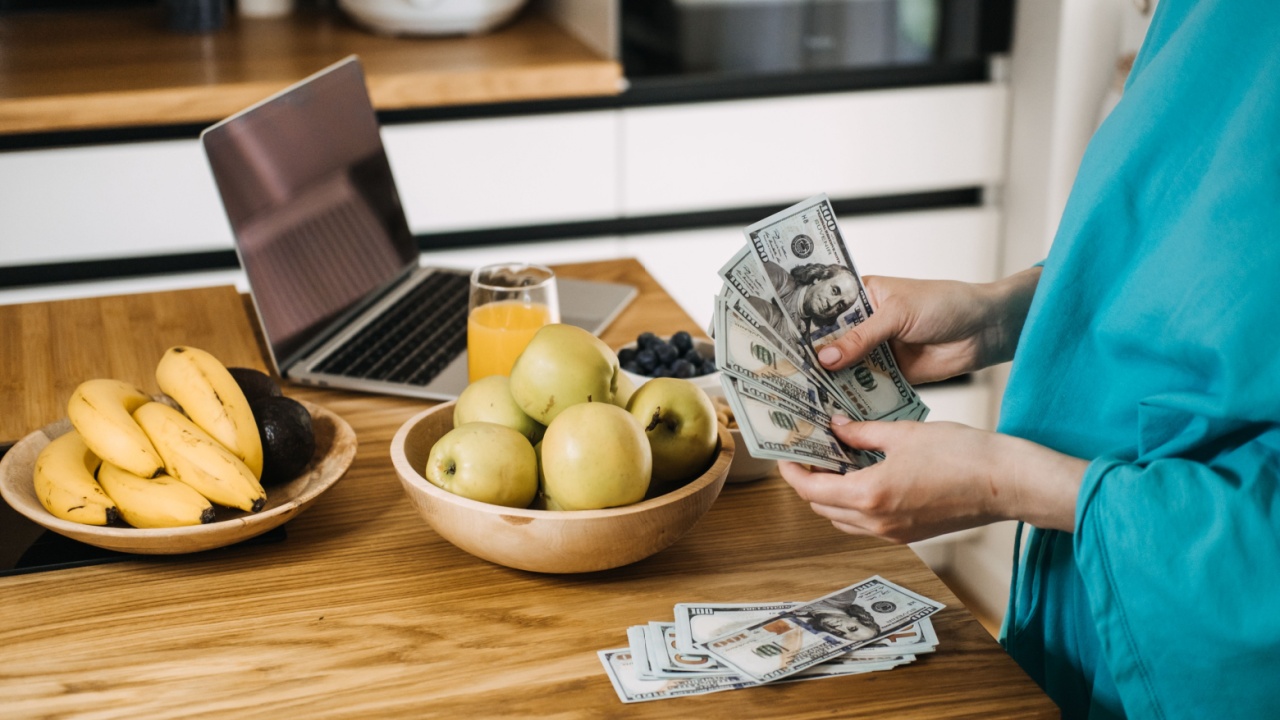 Woman budgeting money while preparing fresh meals in a cozy kitchen. Budgeting for healthy living, mindful spending, and cost-effective nutrition.