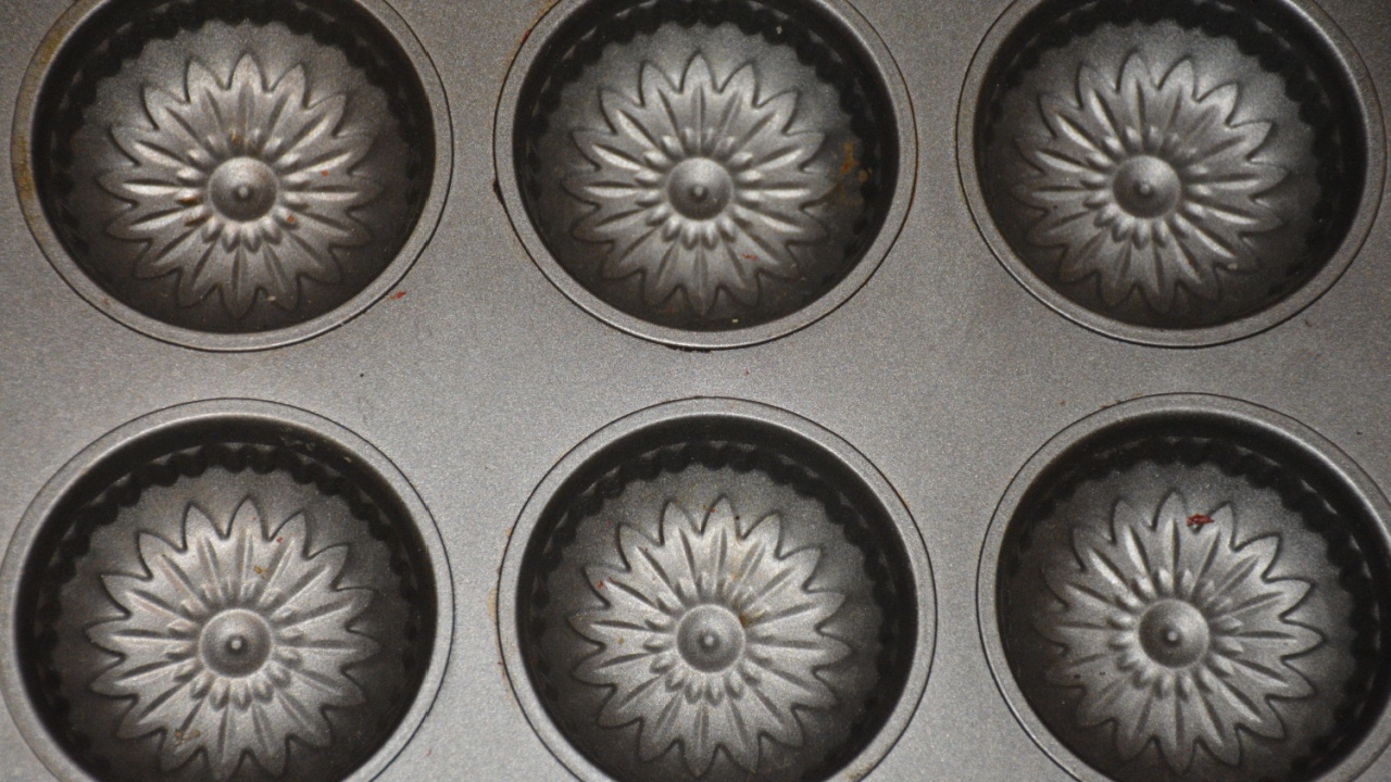 Decorative metal muffin tin with intricate sunburst design in each cavity.
