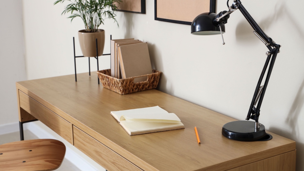 Modern workspace with wooden table, stylish desk lamp and books at home