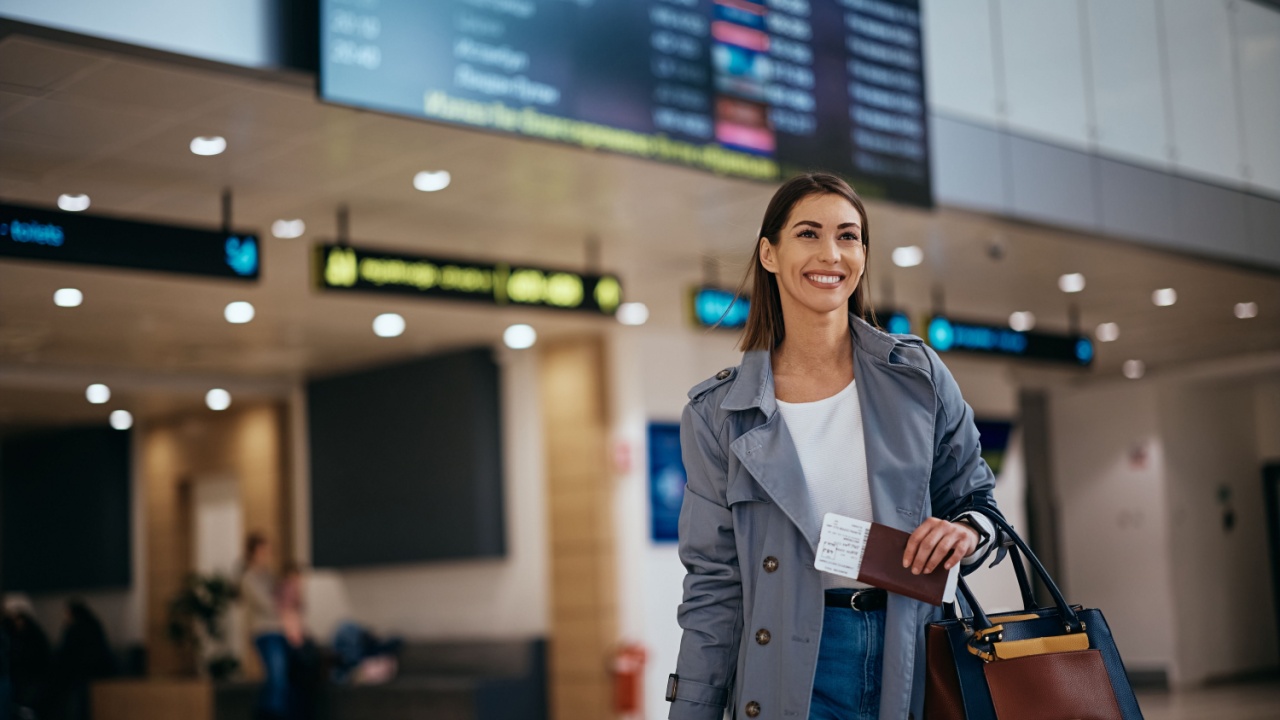 Happy female traveler walking towards departure gate at the airport. Copy space.