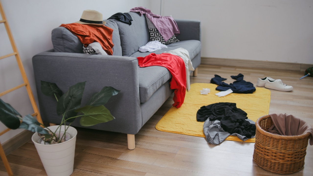 Portrait Of Messy Room With Dirty Clothes And Stuff On Sofa And Floor