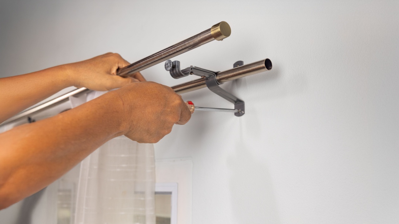 Handyman repairman hanging and fixing the curtain rod on the window