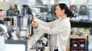 Woman choosing kitchen equipments at store.