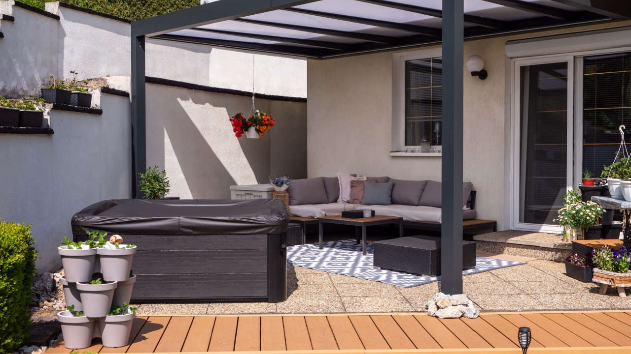 Modern aluminum pergola on backyard patio with outdoor seating, hot tub, and decorative plants in a residential garden.