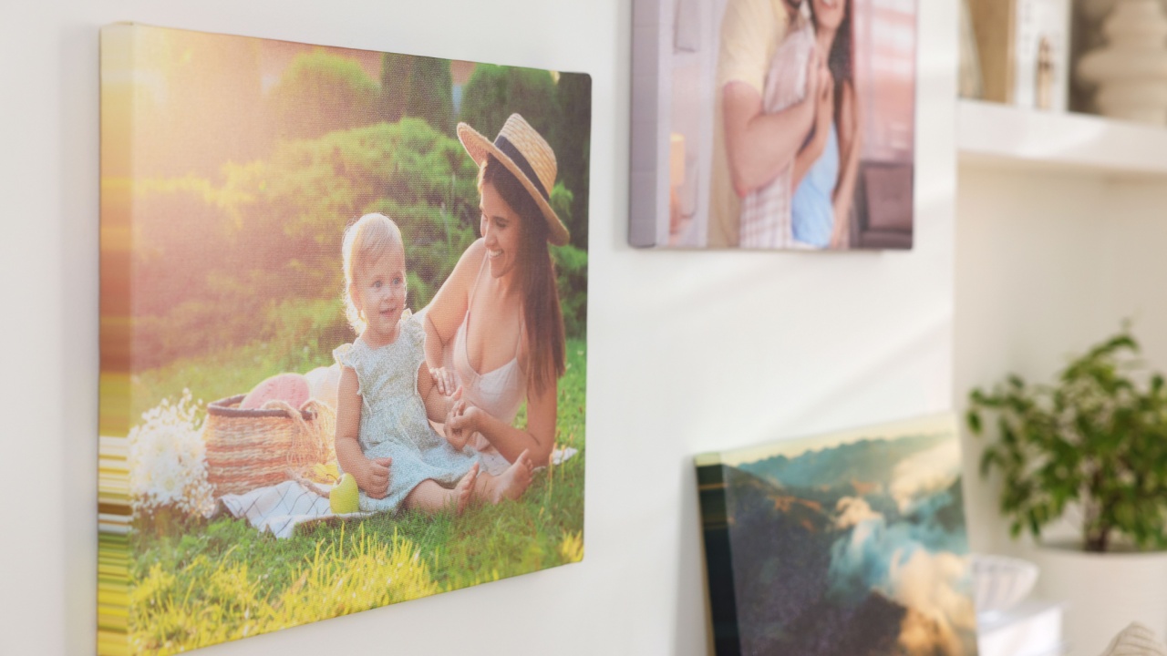 Canvas with different printed photos on white wall indoors, closeup