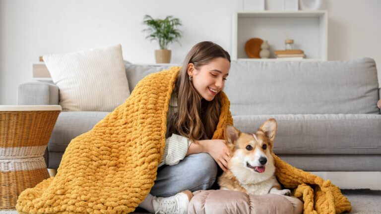 Young woman and Corgi dog with orange plaid on floor at home