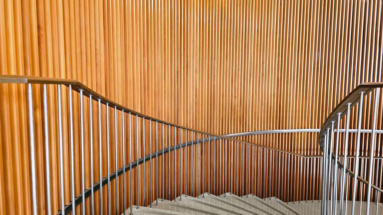 modern spiral staircase with sleek metal railings and a vertical wooden slat wall