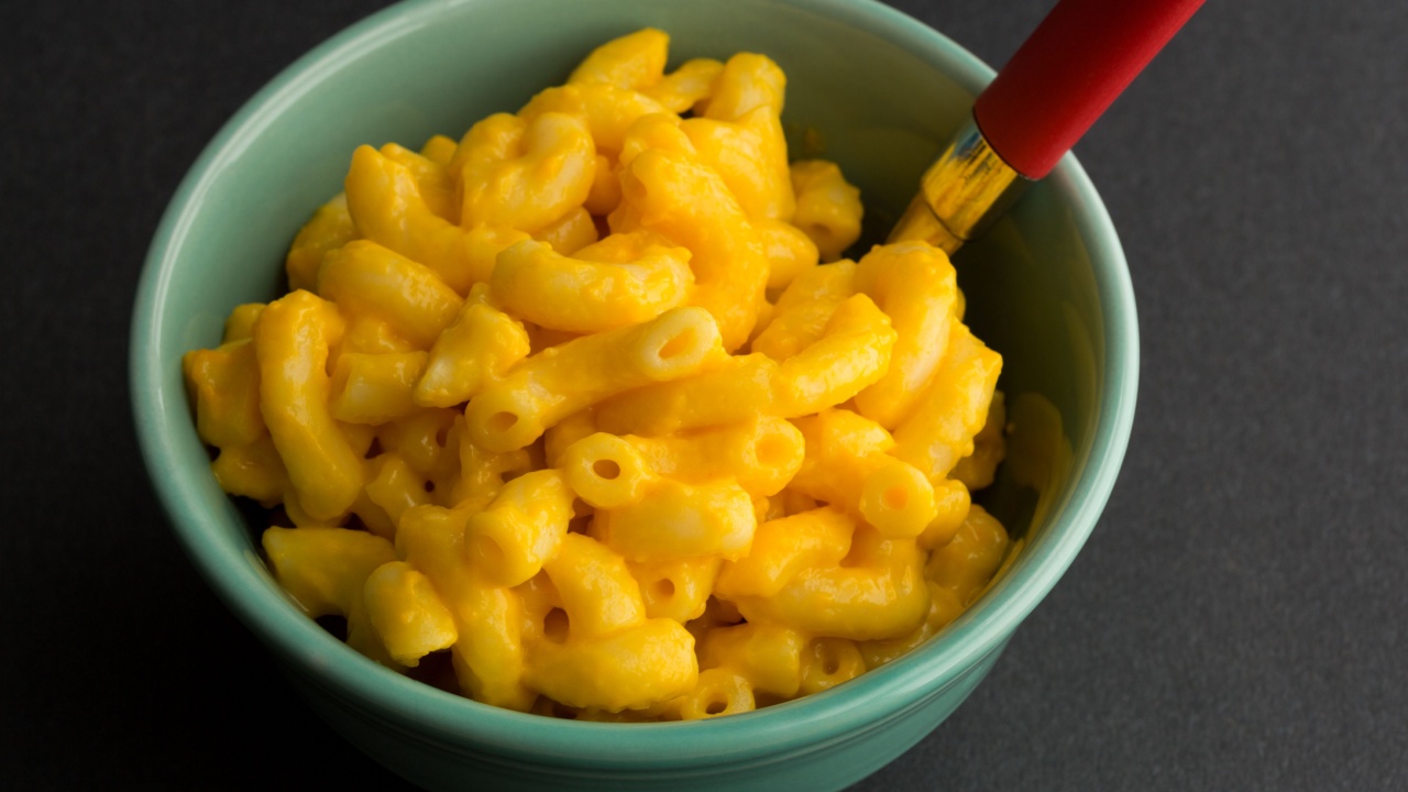 Close view of a small bowl of macaroni and cheese with a spoon .
