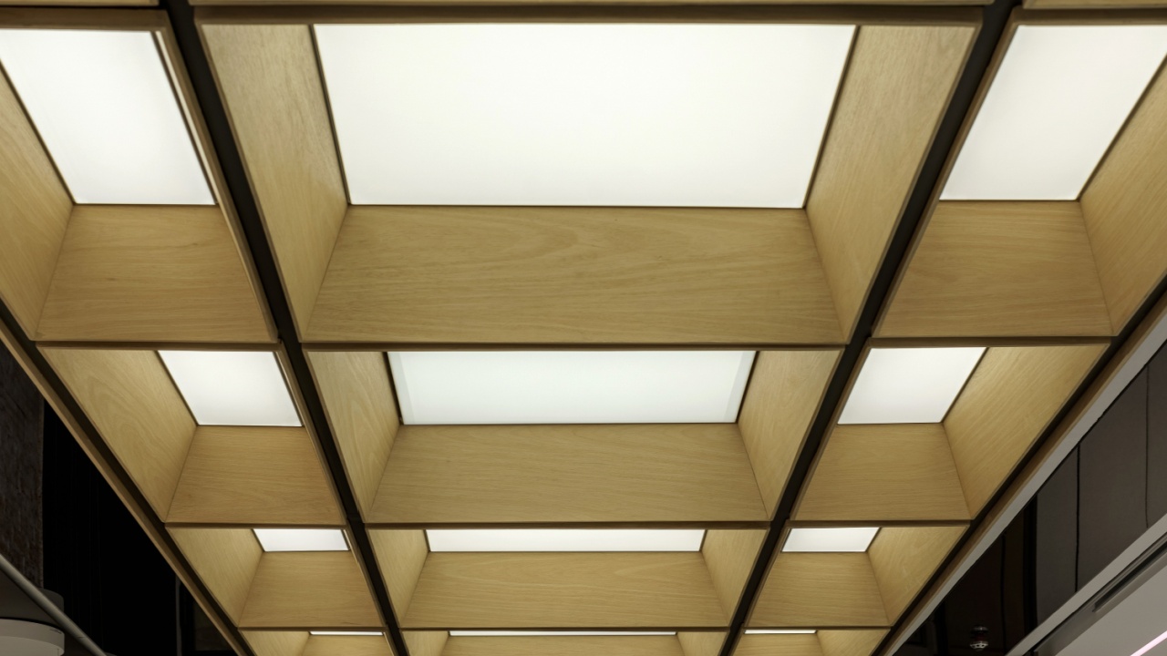 Modern coffered ceiling with integrated lighting. Architectural detail of a wooden grid with backlit panels, creating a geometric and luminous design.