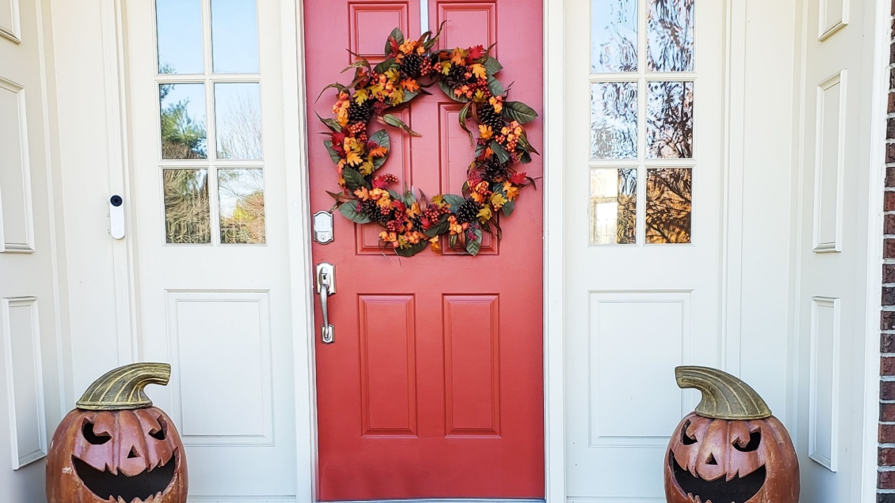 Autumn harvest decor featuring jack-o'-lanterns and a vibrant wreath adorns the front porch.