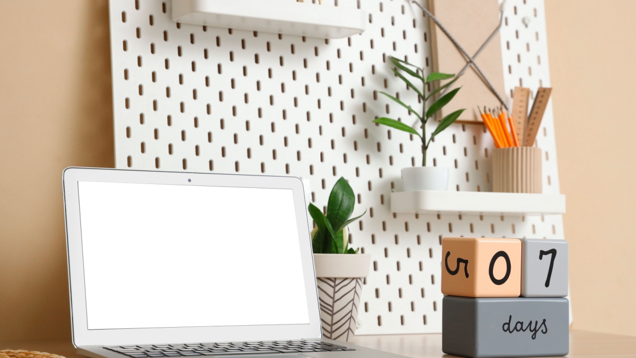 Modern laptop, cube calendar and pegboard with stationery on table