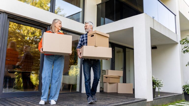 Senior couple enjoying moving day carrying boxes