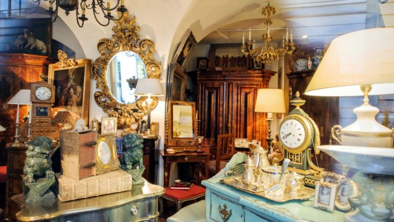 VIENNA, AUSTRIA - JULY 4, 2011: Antiquities shop window shopping seen from the street - Kohlmarkt street in Vienna. The vintage store sells old clocks, old mirrors, old furniture, vintage objects