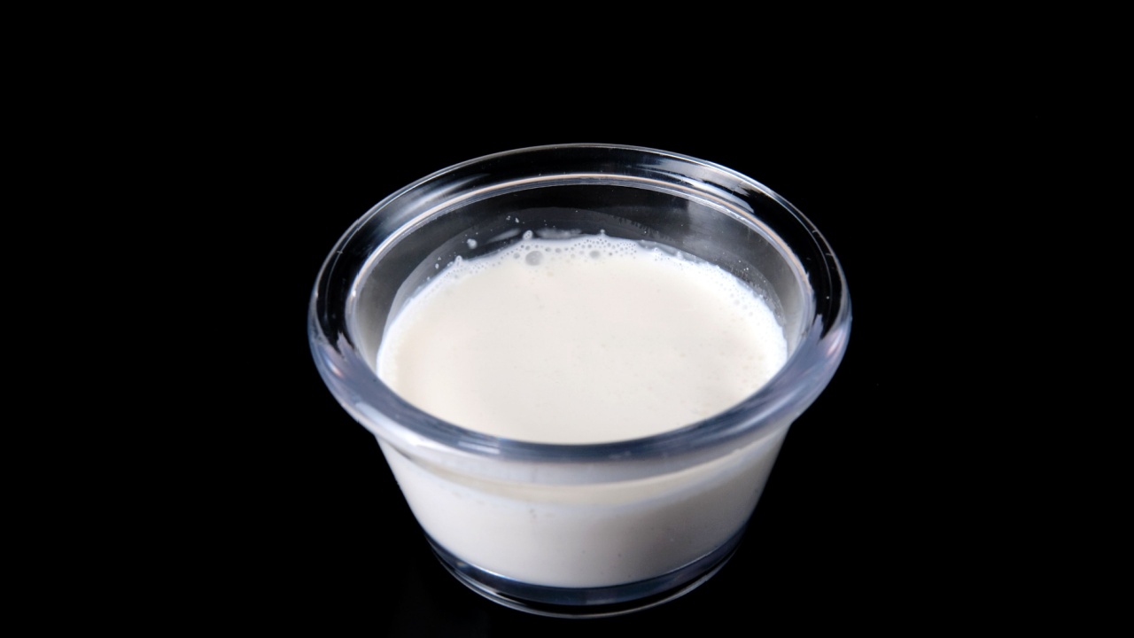 closeup photo of heavy white cream in a small clear ingredient cup over a black background