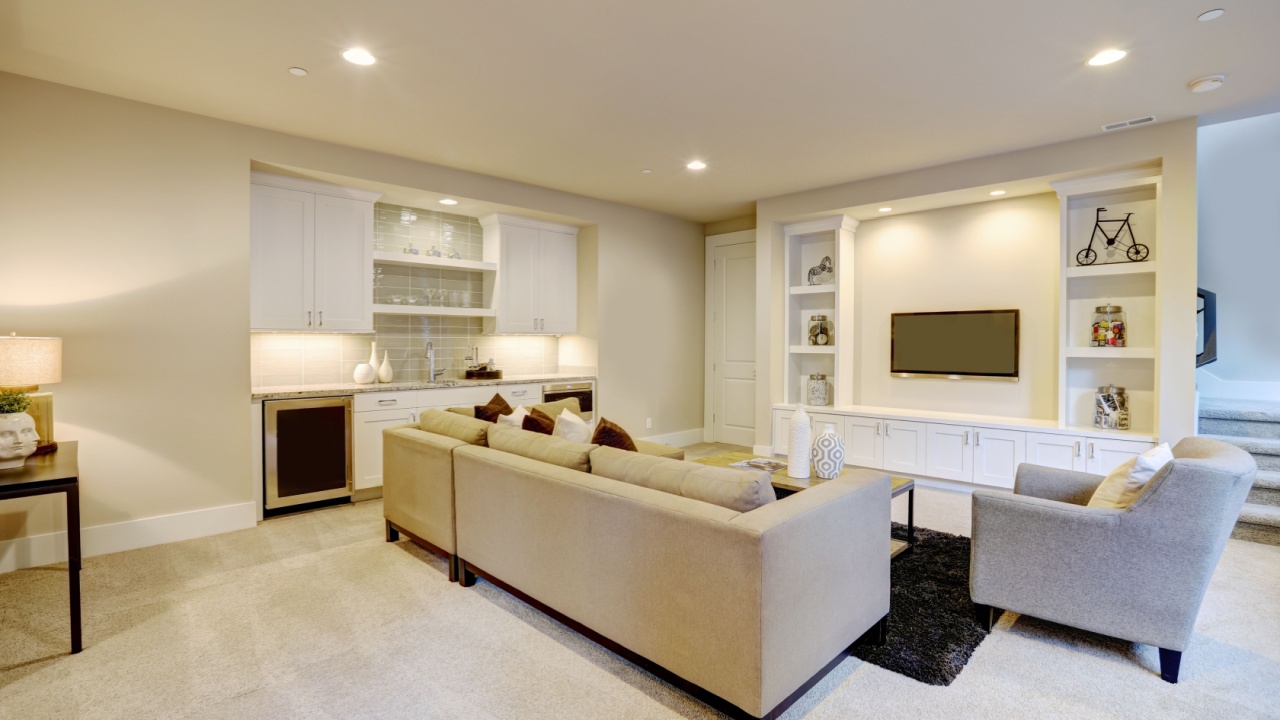 Chic basement features a gray sectional facing a white built-in tv cabinet and wet bar mounted to a wall. Northwest, USA