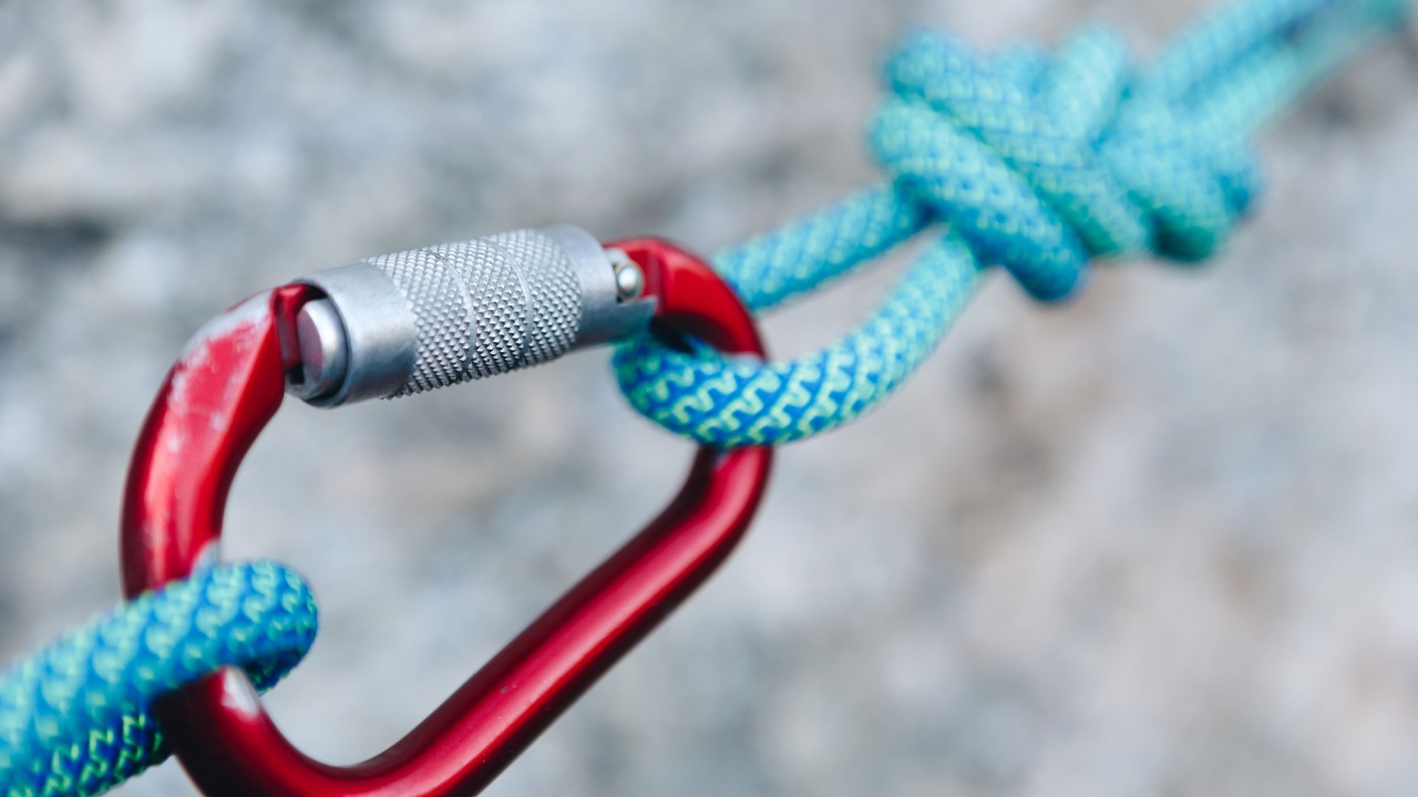 carabiner hook with a climbing rope on rocky background. Climbing concept