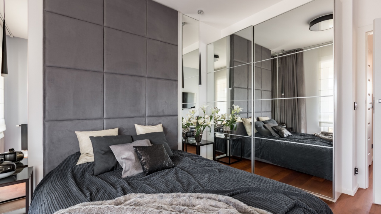 Luxurious bedroom with mirrored wardrobe, double bed and upholstered wall