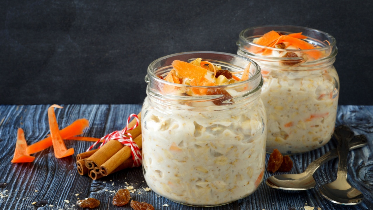 Carrot cake overnight oats with nuts and raisins in jars on a rustic dark background