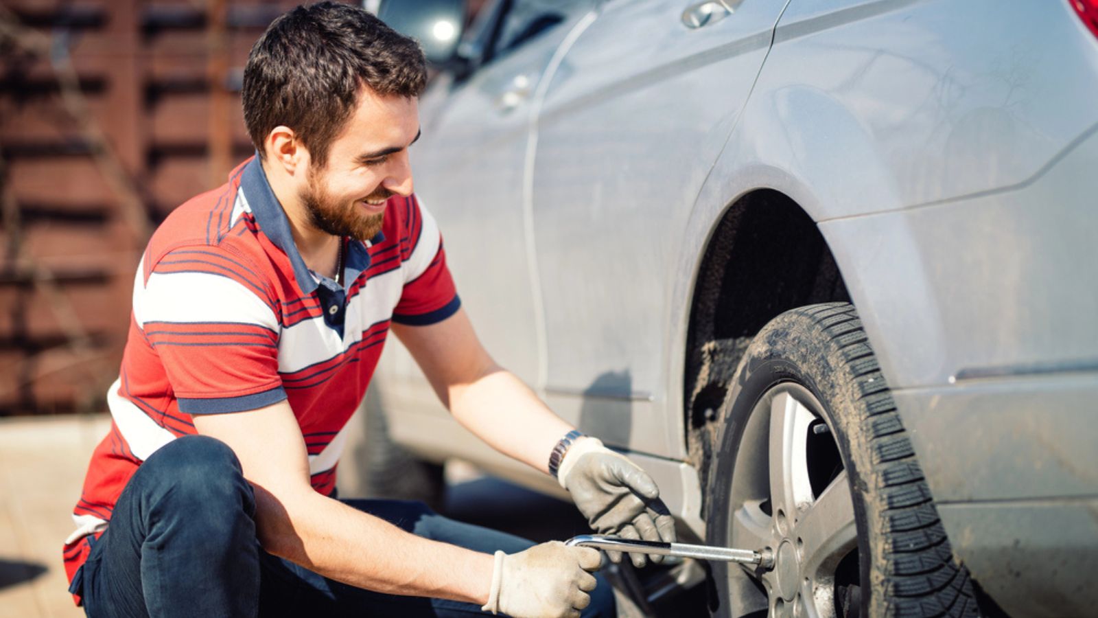 Smiling man and mechanic changing tires, using jack and wheel wrench
