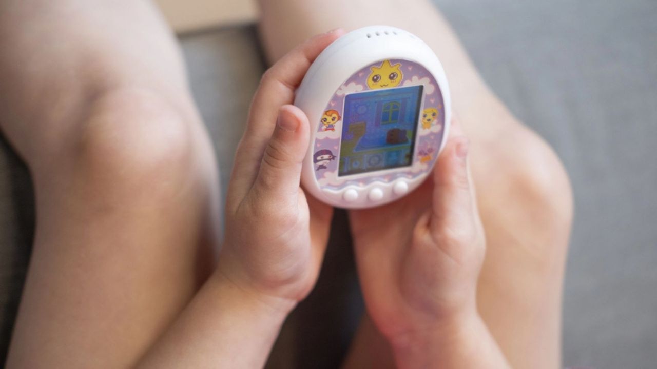 Child hand gently cradle Tamagotchi toy, evoking nostalgia for popular virtual pet craze 1990s, developing empathy, Nurturing childhood memories, Frankfurt