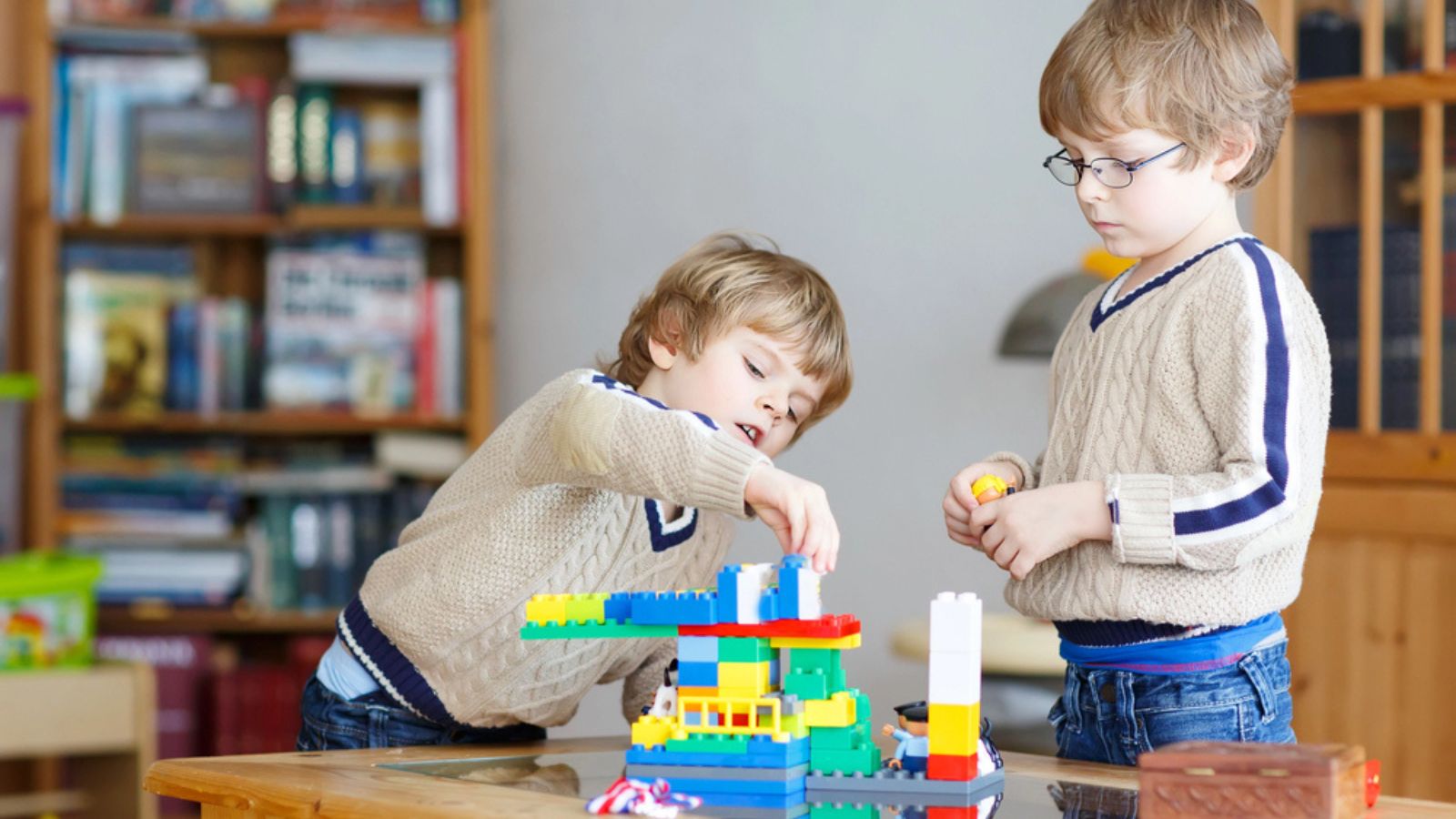 Two little kid boys playing with lots of colorful plastic blocks indoor. Children having fun with building and creating.