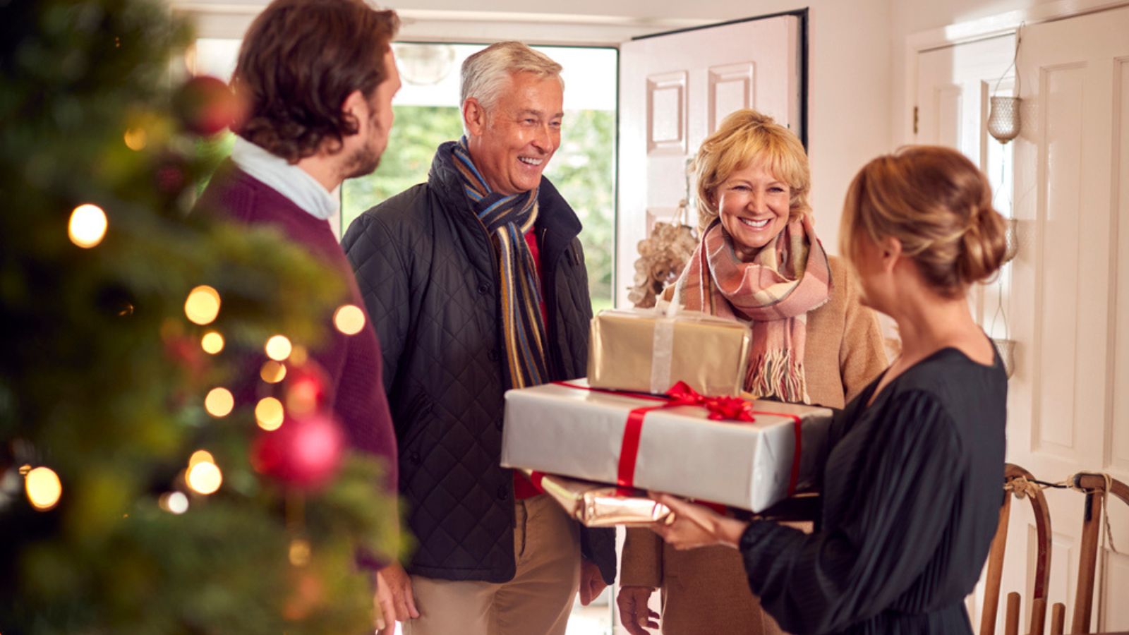 visitor Couple Greeting Senior Parents As They Arrive With Presents To Celebrate Christmas