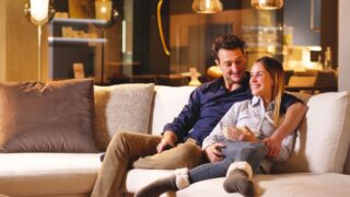 A couple of lovers watch television embraced on the sofa in the new house and watch a movie together. Concept of leisure, relax, tv. Gold interior house