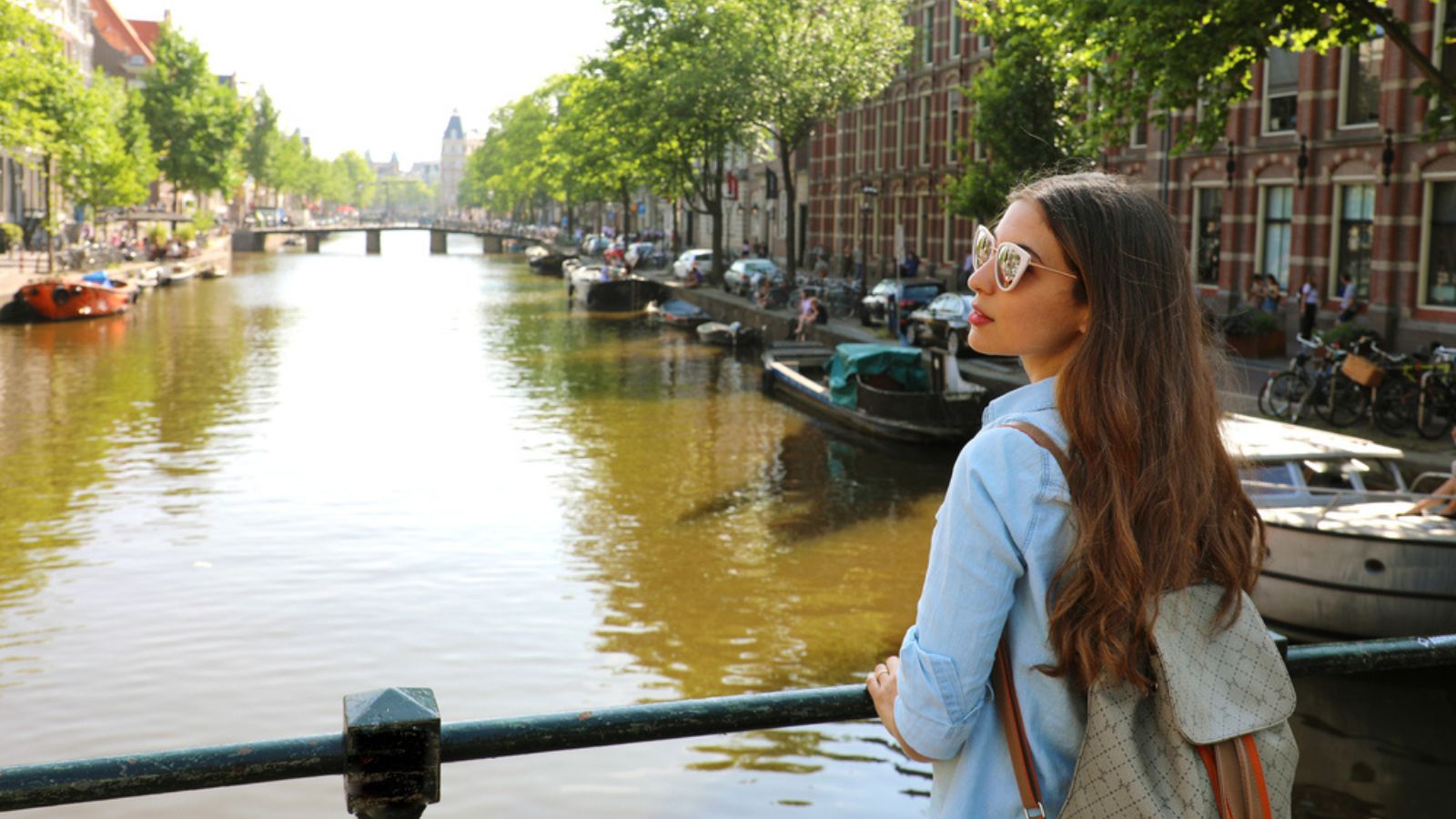 Back view of young woman looking to the side on Amsterdam channel, Netherlands, Europe