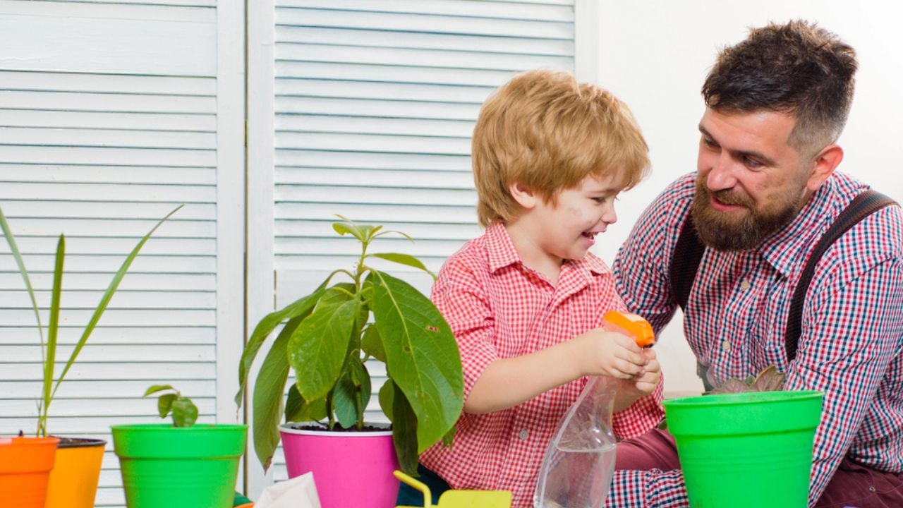 Child son with father growing plant in pot. Family holiday and togetherness.