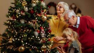 Grandparents and little girl decorate a Christmas tree