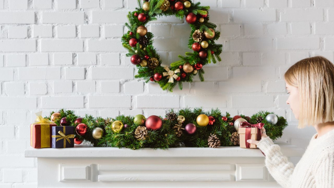 Christmas wreath and decorations over fireplace mantel with white brick wall