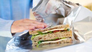 Close Up Of Woman Wrapping Sandwich In Non Reusable Aluminium Foil