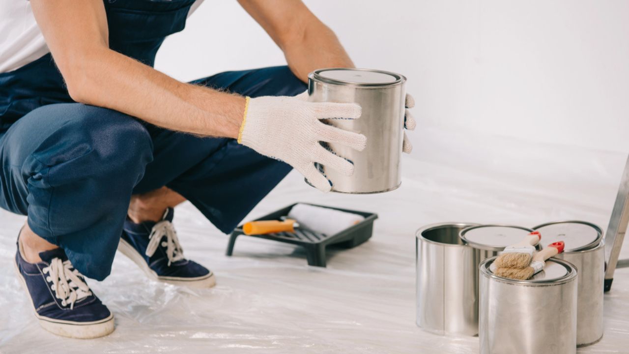 Cropped view of painter in uniform holding can with paint