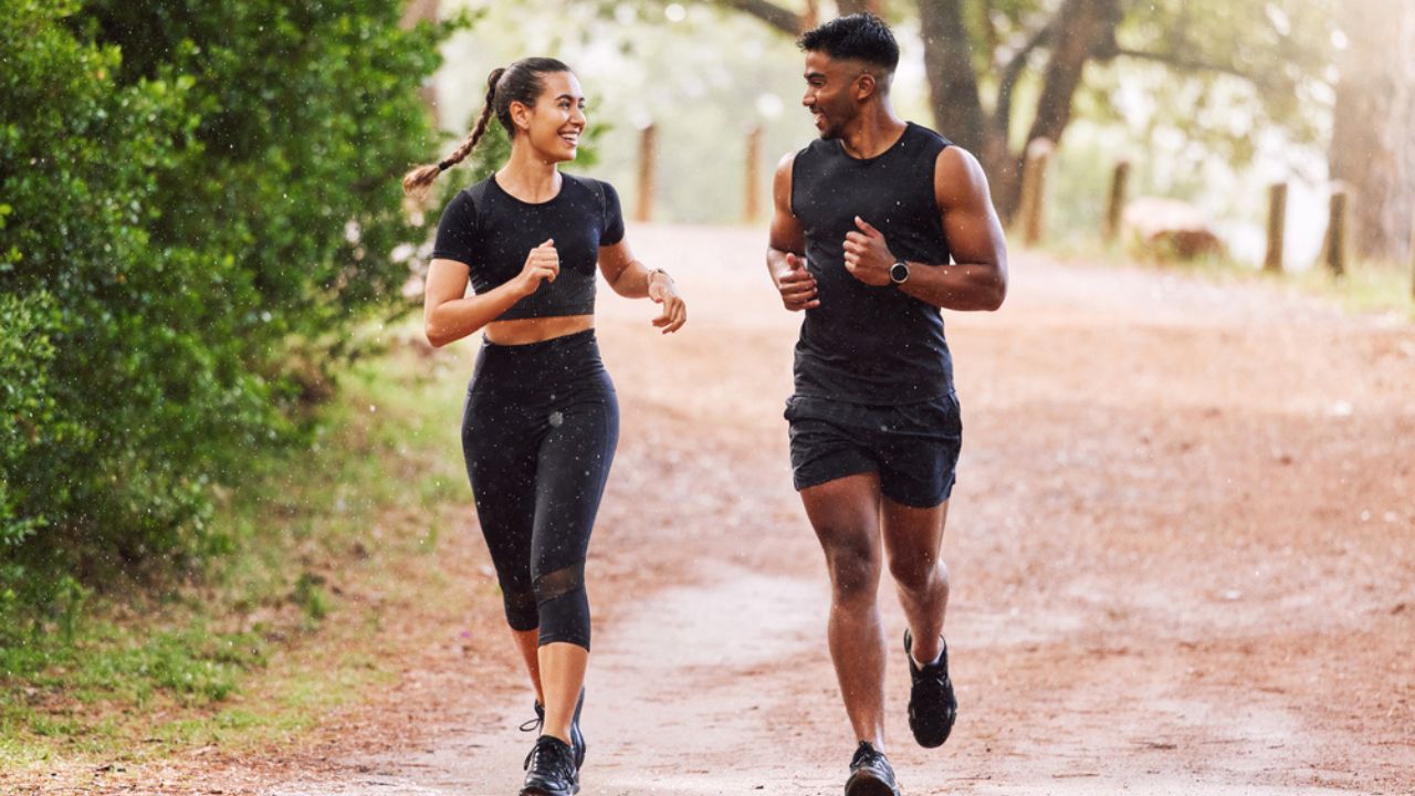 Fitness, exercise and happy couple out running or jogging on a forest trail or park outdoors