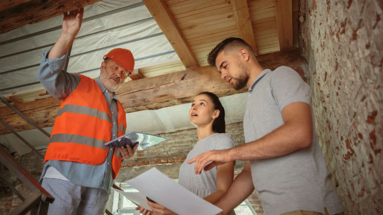 Foreman or achitect shows house, office or store design plans to a young couple