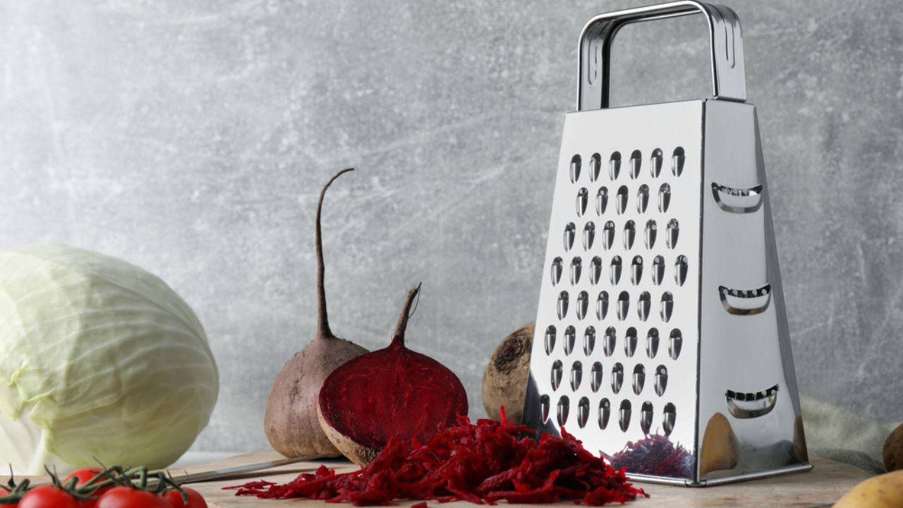 Grater and fresh ripe vegetables on table