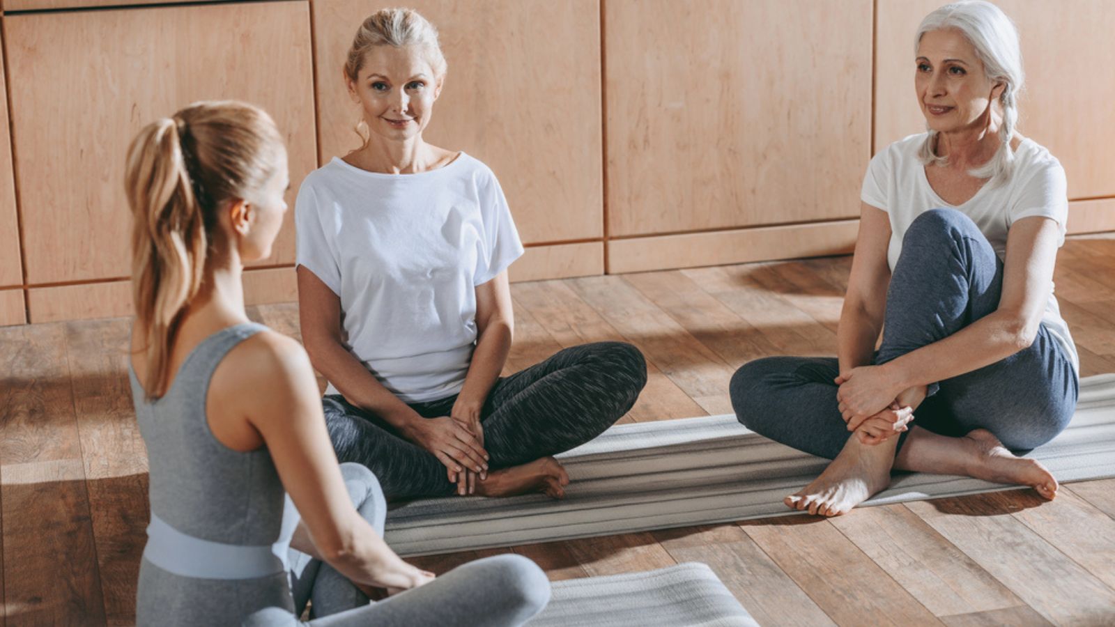 Group of women sitting on yoga mats in studio