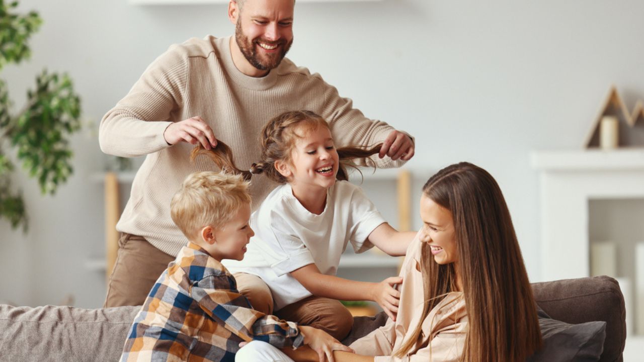 Happy family mother father and kids having fun at home on the couch