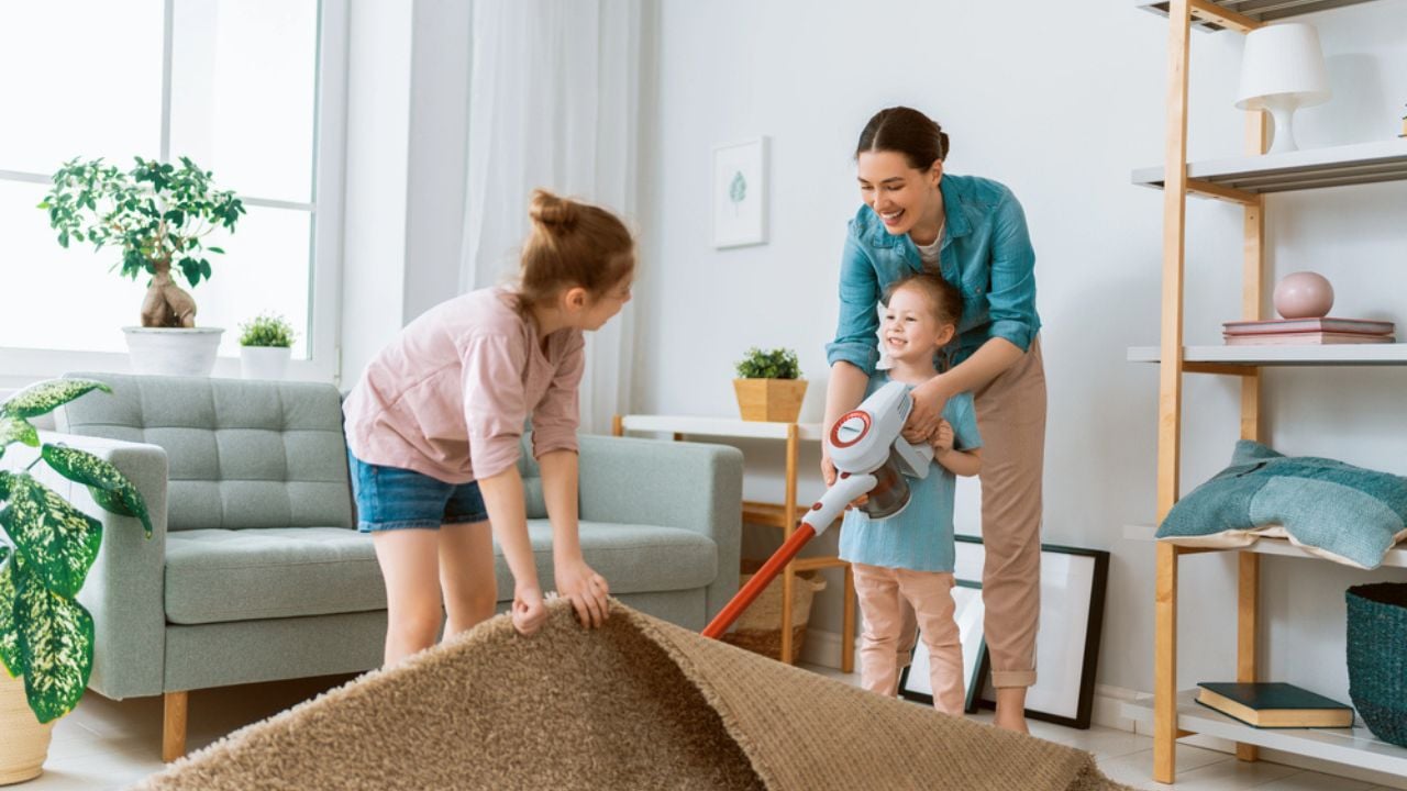Happy family vacuuming the room. Mother and daughter doing the cleaning in the house.
