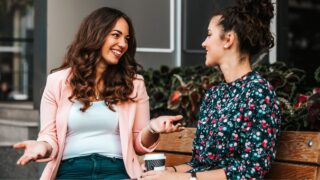 Happy female friends laughing and talking while looking each oth