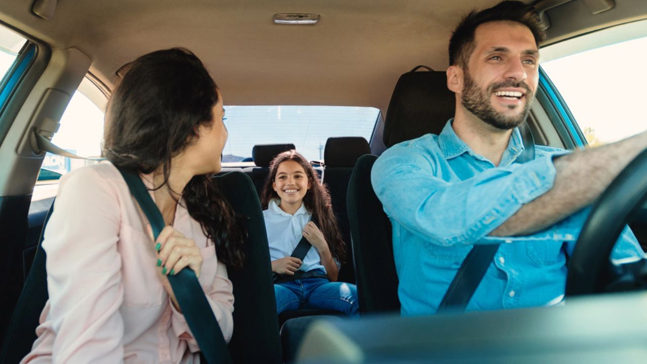 Happy parents and daughter sitting in auto during road trip,