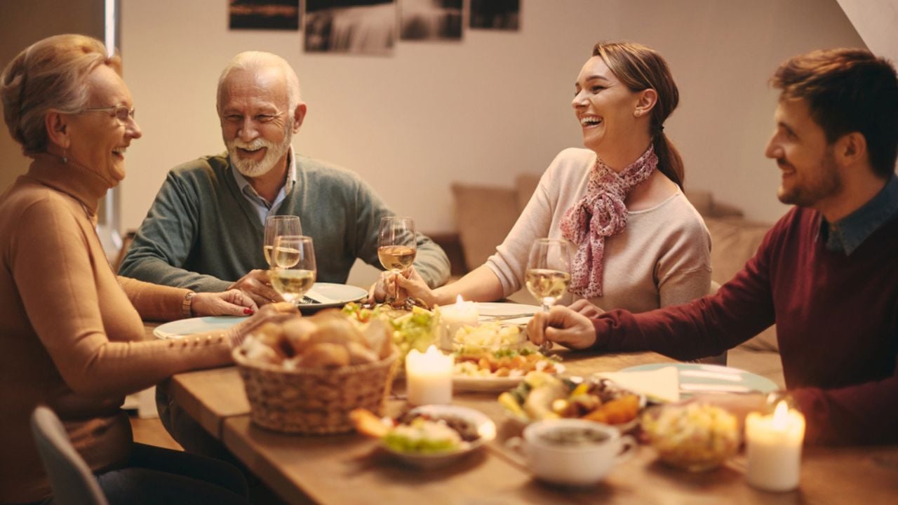 Happy senior couple and their adult children having fun while drinking wine and communicating at dining table.