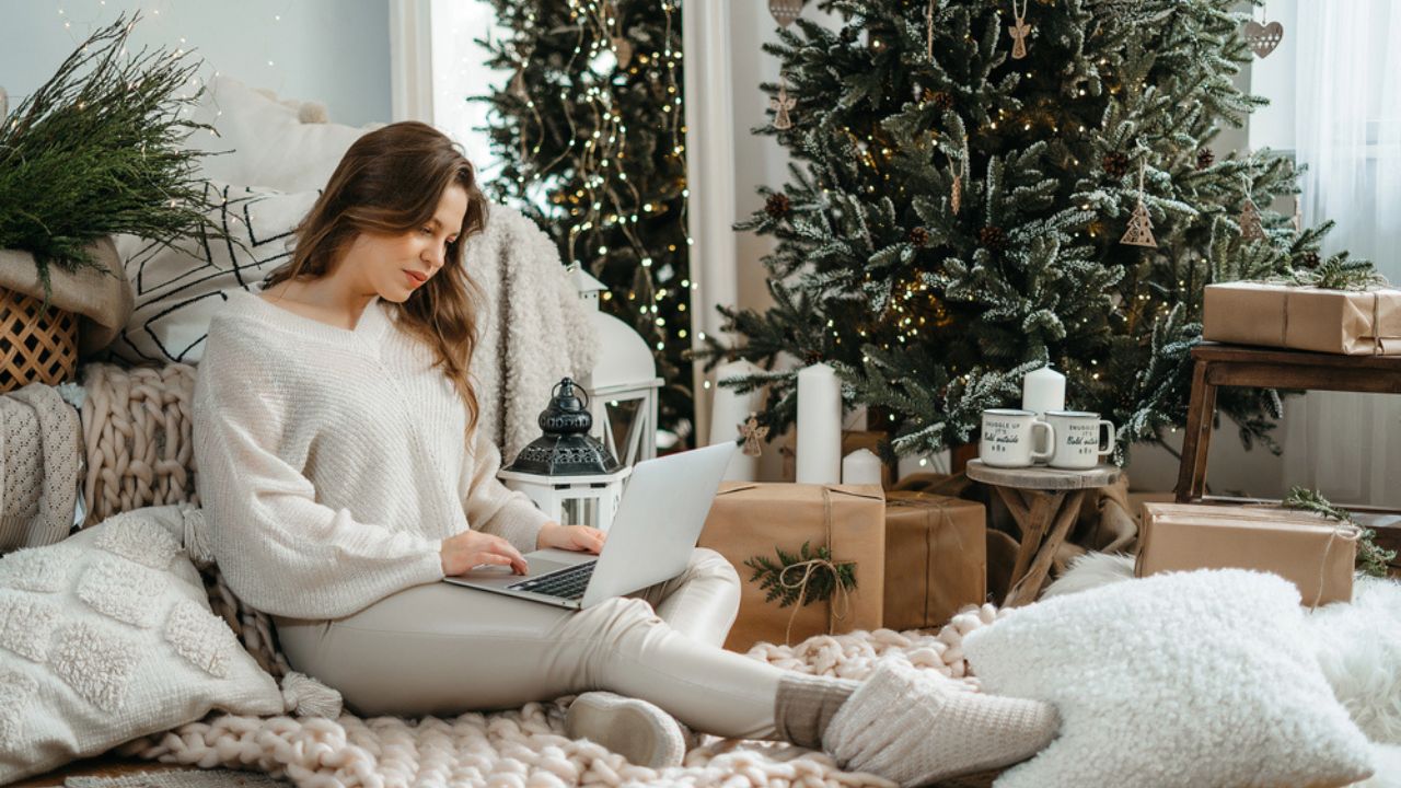 Head shot smiling young caucasian woman in warm winter clothes looking at computer tablet screen.