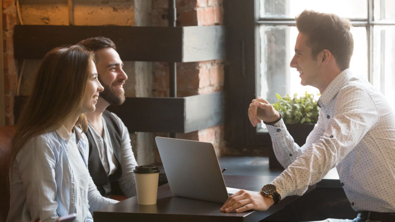 Male architect consulting excited millennial couple in coffee shop.
