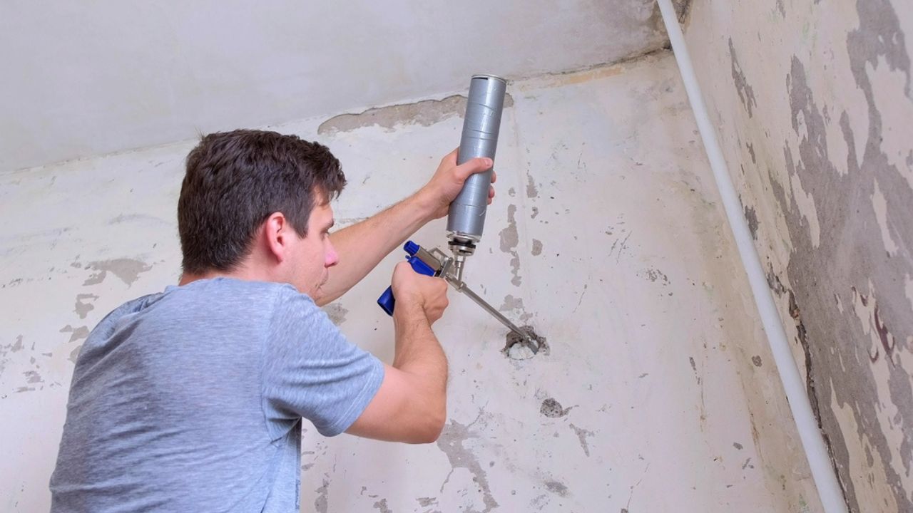 Man fills hole in wall of concrete slab mounting foam making repairs at home