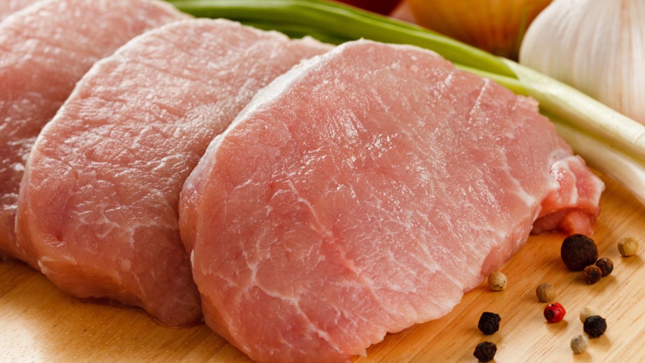 Raw pork chops on cutting board and vegetables