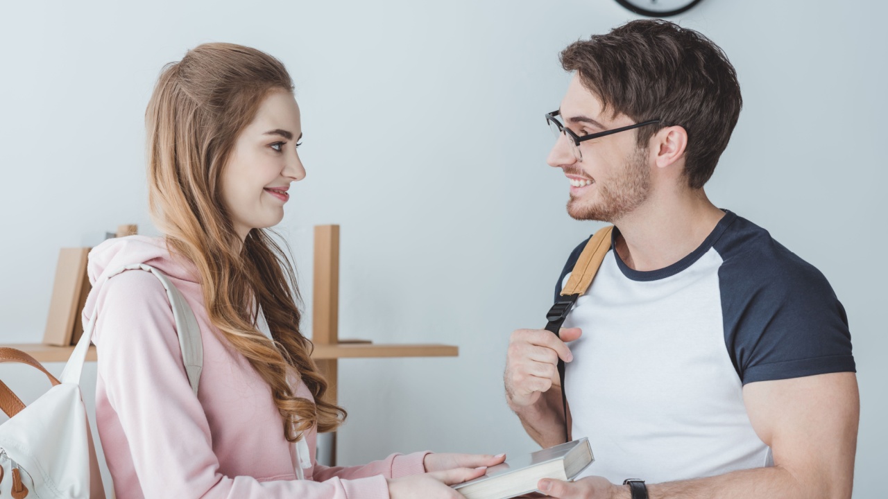 young attractive girl giving book to her friend