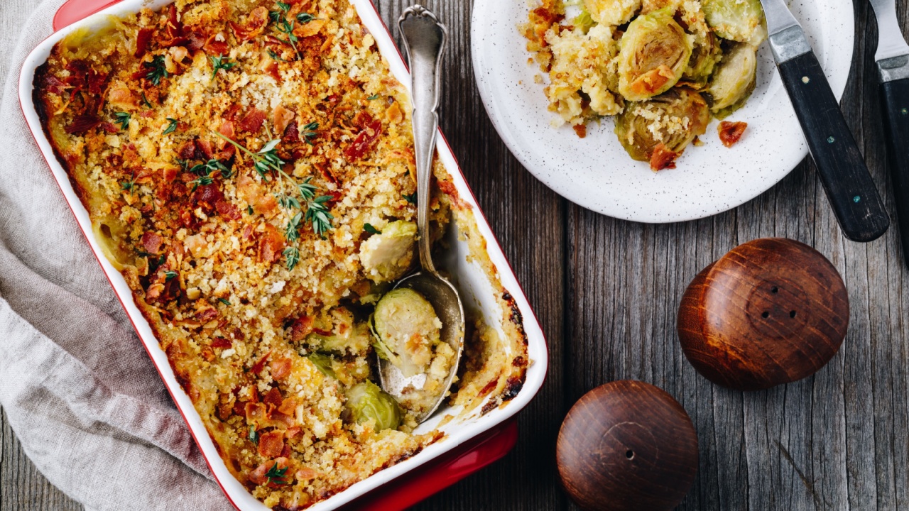 Baked brussel sprout gratin with a bacon and bread crumbs on wooden background