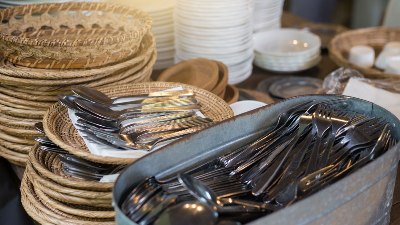 Equipment for eating in the food court. Spoon and fork are arranged orderly and convenient to use. White dishes and cups of soup are arranged in layers on wood background.